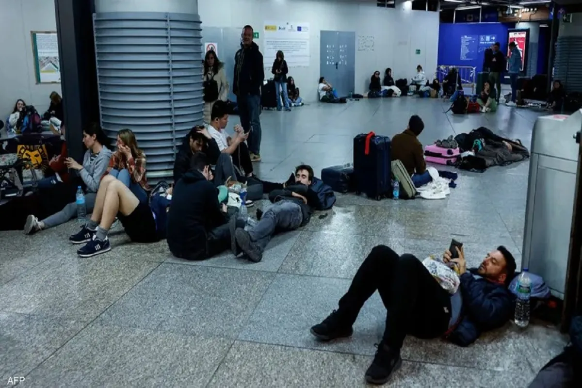 مسافرون في محطة قطارات بإسبانيا مستلقون انتظارًا لعودة التيار الكهربائي