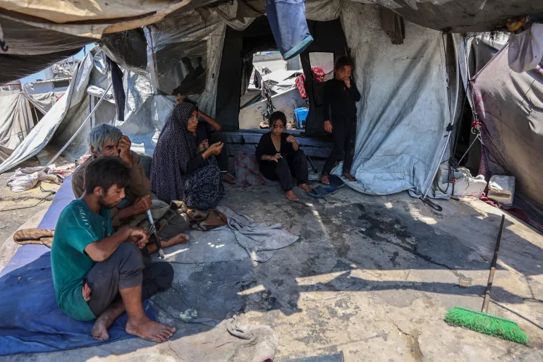 عائلة فلسطينية تجلس أمام خيمتها في حي الدرج بغزة (الفرنسية)
