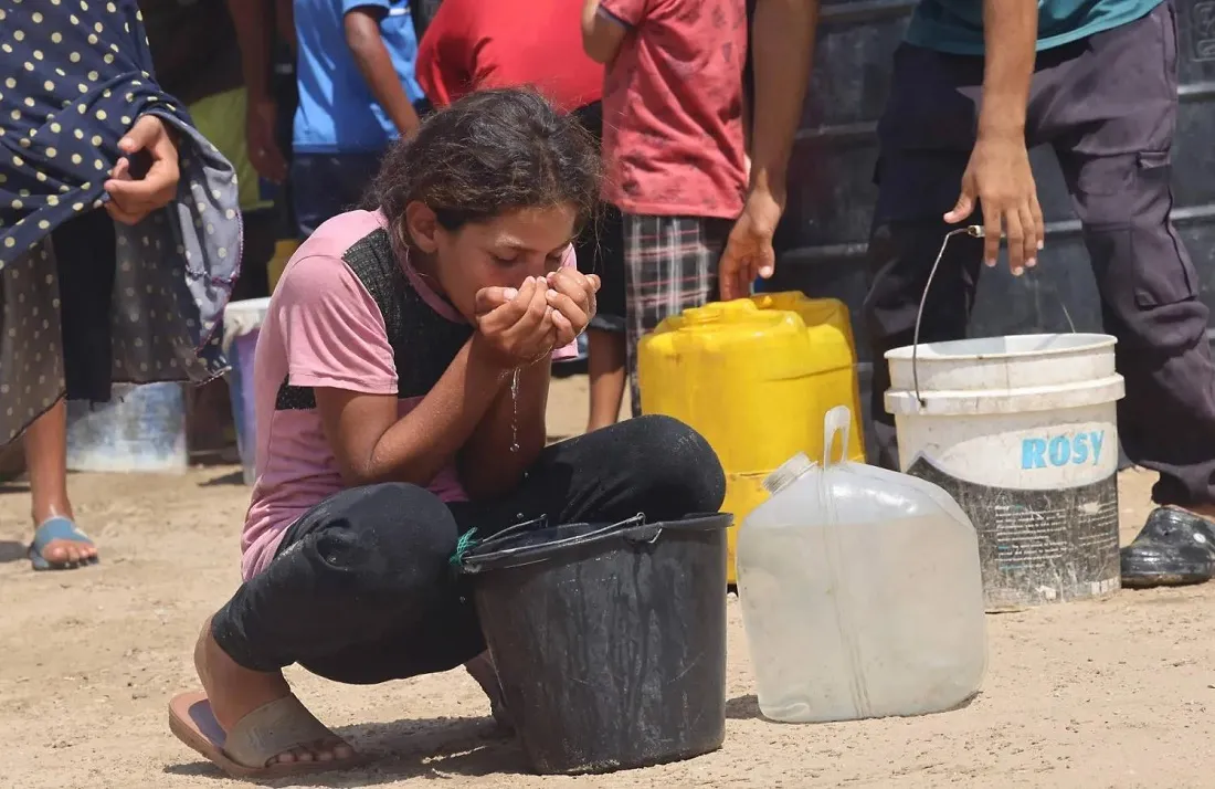 مرض نادر يصيب أهالي غزة .. وفي الصورة فتاة تشرب الماء من دلو بحثاً عن الماء بقطاع غزة (أ.ف.ب)