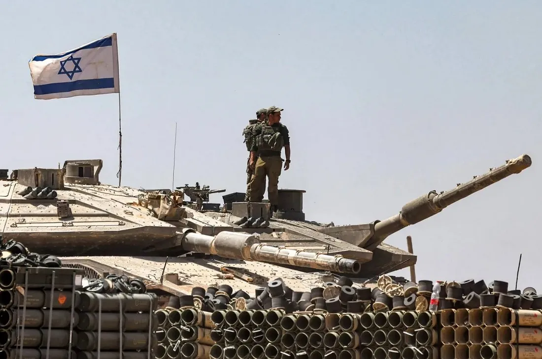 جنود من الجيش الإسرائيلي يقفون فوق برج دبابة متمركزة في جنوب إسرائيل بالقرب من الحدود مع قطاع غزة (أ.ف.ب)