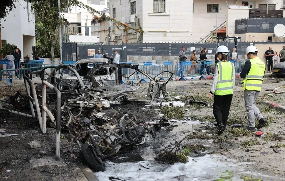 خدمة الطوارئ في إسرائيل يعاينان سيارات محترقة جراء اعتراض صواريخ باليستية من إيران في تل أبيب السبت(إ.ب.أ)