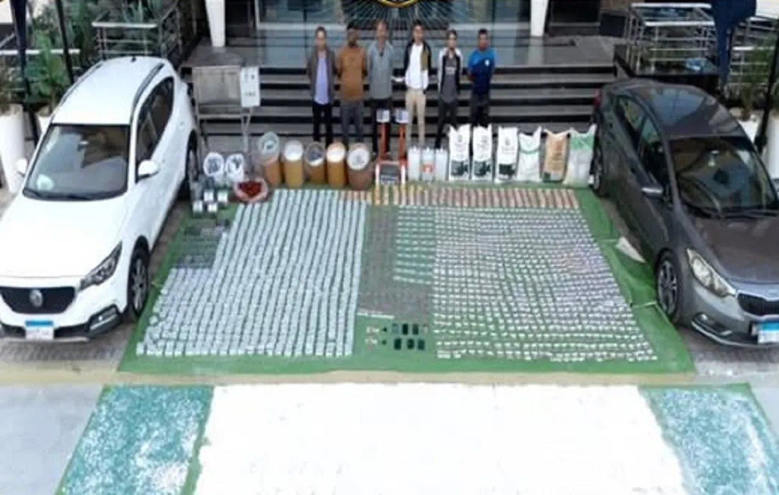 عدد من التشكيل العصابي المتهم بتهريب المخدرات وأمامهم المضبوطات والسيارات المستخدمة في عمليات التهريب